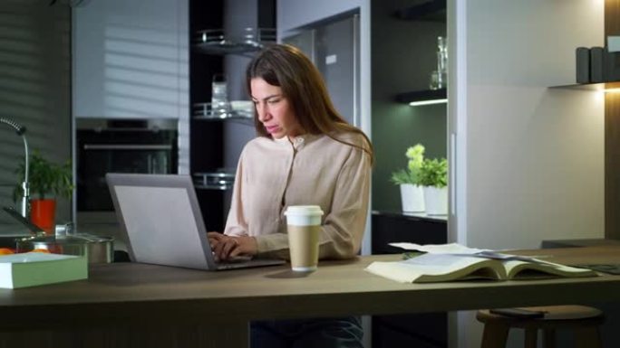 年轻成功的女商人打开笔记本电脑，在家在厨房里在线工作，喝咖啡和检查笔记的肖像。学生准备远程考试，写论