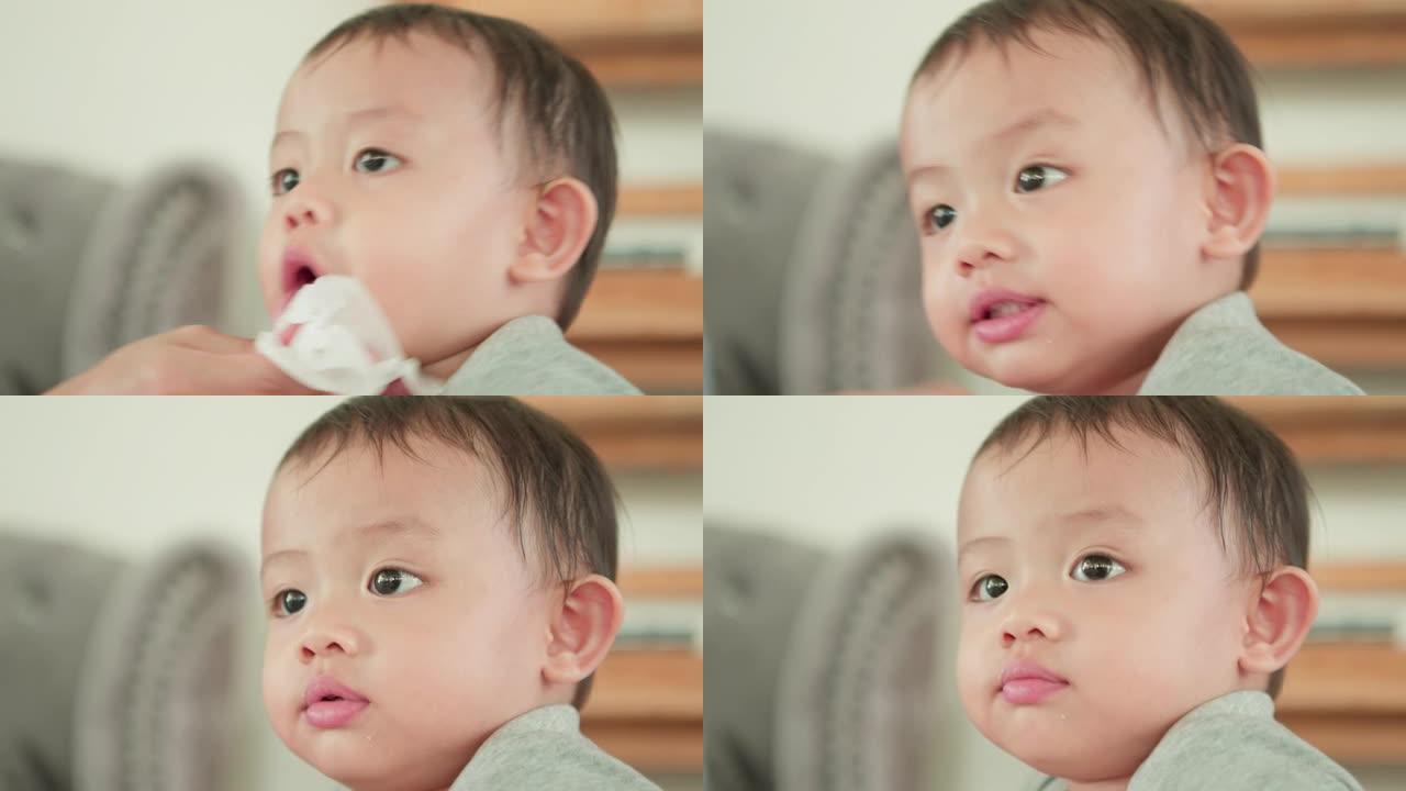 可爱的亚洲小男孩的特写脸。妈妈一边擦孩子的嘴。为人父母，母亲节概念。