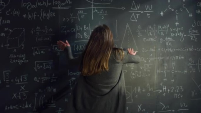 后视图: 女人用粉笔在黑板上写数学公式，沮丧并愤怒地擦拭它。女科学家试图解方程，被卡住时感到愤怒
