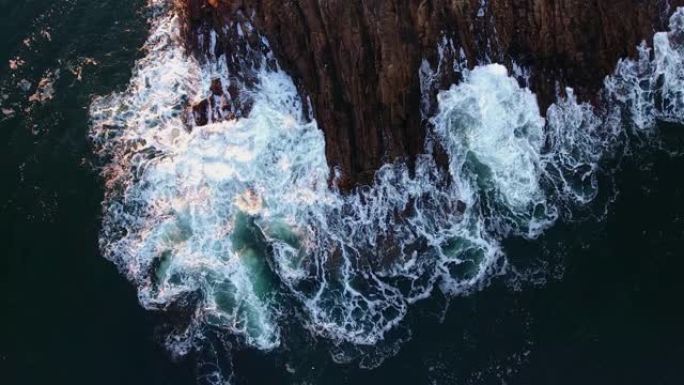 海洋泡沫波浪撞击大石头和悬崖的俯视图