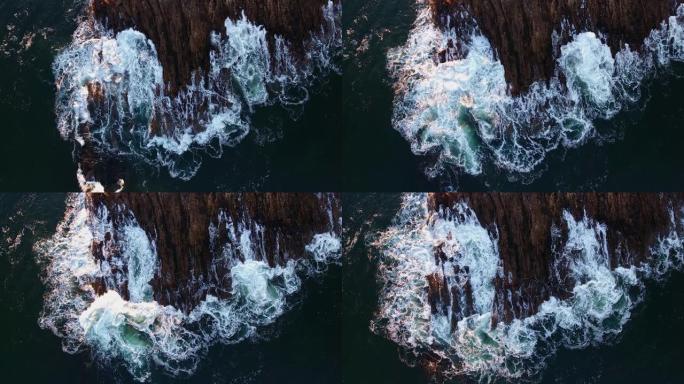 海洋泡沫波浪撞击大石头和悬崖的俯视图
