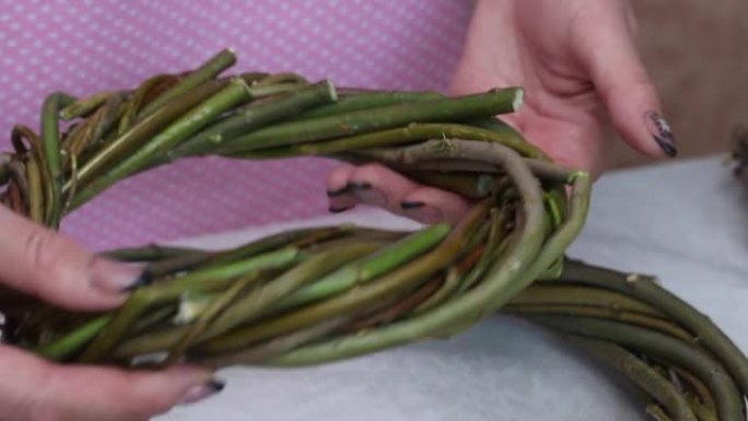 一名妇女检查用藤蔓编织的自制花环。不同的尺寸。特写。
