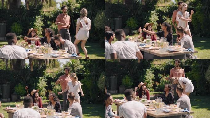 快乐的夫妇在花园派对上与朋友跳舞庆祝，在美丽的夏日享受野餐午餐，激动人心的周末聚会
