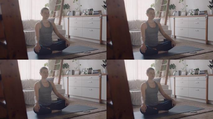 健康瑜伽女人在家锻炼，在客厅练习冥想，享受早晨的正念锻炼