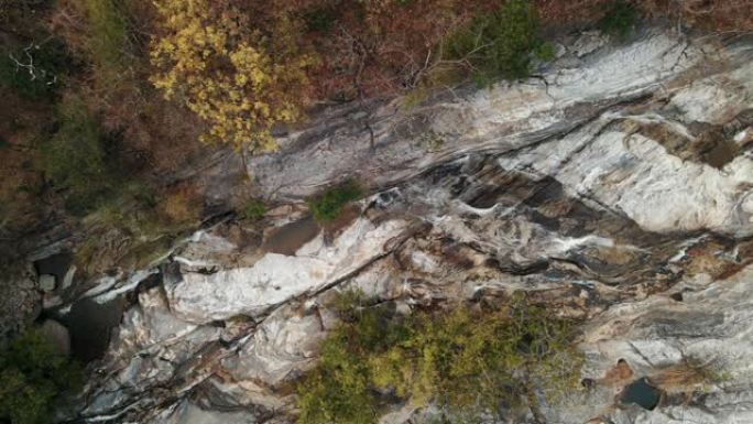 无人驾驶飞机以白水急流和岩石巨石在瀑布上升起。