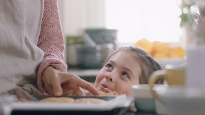 美丽的小女孩偷饼干和妈妈在厨房里烤偷偷摸摸的孩子享受美味的食物在家里玩得开心