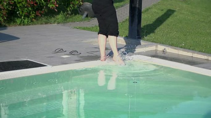 女人试试游泳池的温度。