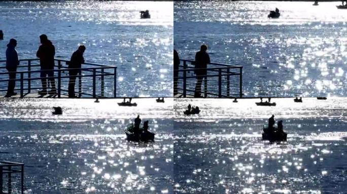 渔民在波光粼粼的蓝色水域中捕鱼，并乘船