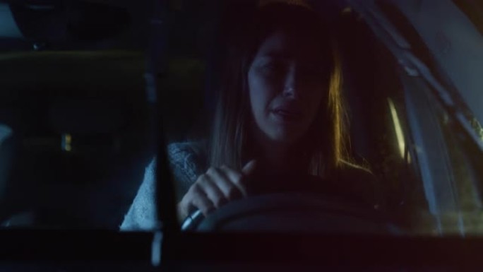 一个心烦意乱的年轻女子在雨夜开车，哭着抽泣。女司机对坏消息感到沮丧，情绪化，对家庭或事业问题感到悲伤