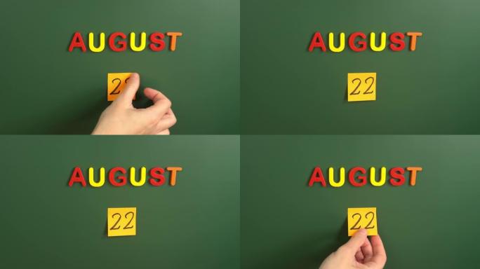 8月22日日历日用手在学校董事会上贴一张贴纸。22 8月日期。8月的第二十二天。第22个日期编号。2