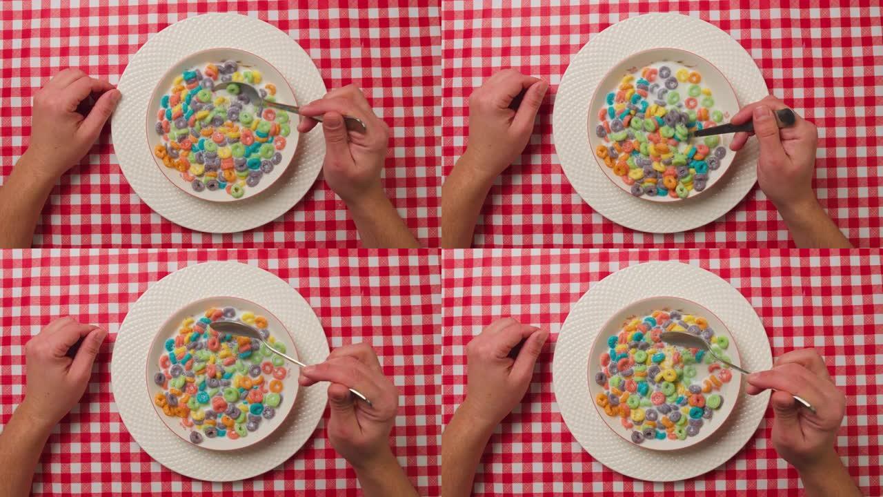 一个孤独的人的手的俯视图在早餐时吃五颜六色的谷物，食欲不振。