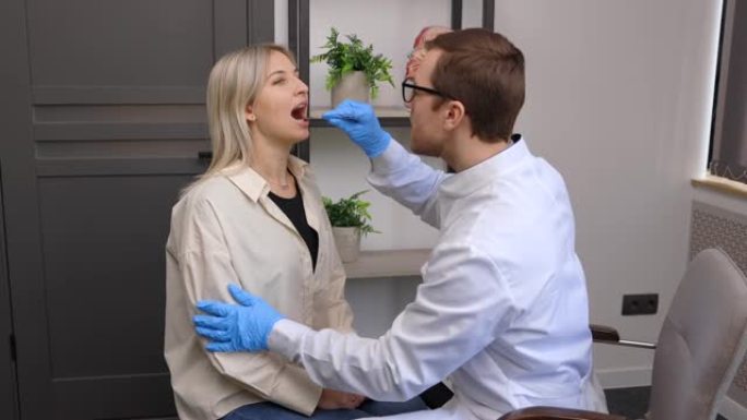 医生用检查刮刀检查病人的喉咙。耳鼻喉科医生给一个女人做喉咙检查。病人张开嘴进行喉咙检查