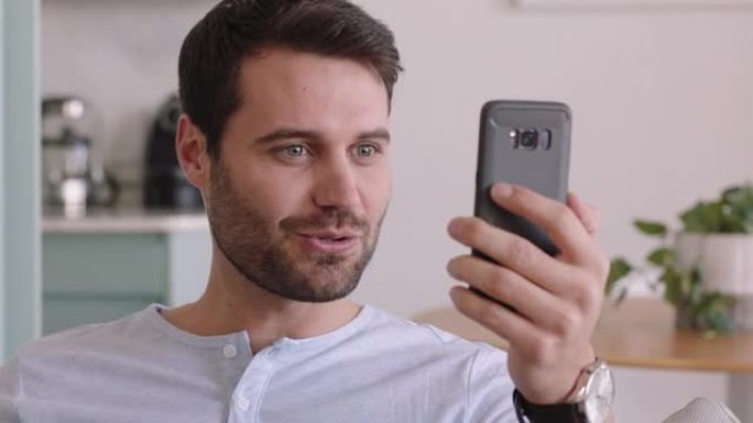 迷人的白人男子在家中使用智能手机进行视频聊天，炫耀发型聊天分享生活方式，享受在线交流