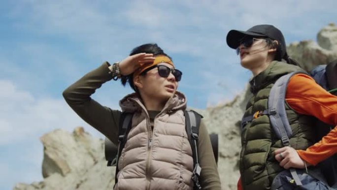 两个亚洲女性朋友徒步旅行，环顾岩石底部