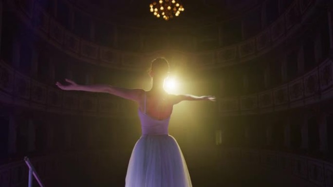 年轻优雅的古典芭蕾舞女舞者以戏剧性的灯光进入经典剧院的舞台的电影背景图。专业女表演者在窗帘打开时开始