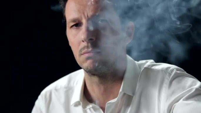 一名男子在黑色背景上吸烟的特写镜头