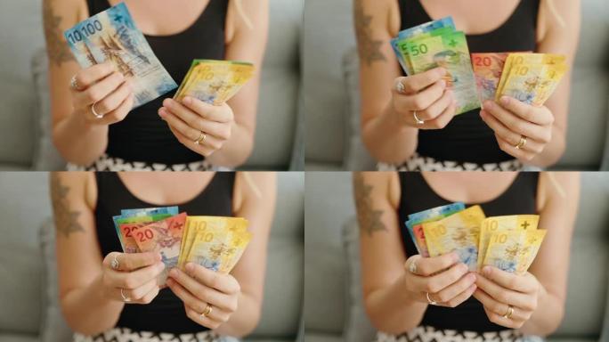 年轻女子在家中数数瑞士法郎钞票