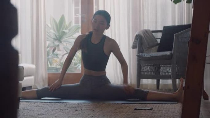 健康的亚洲女性在家锻炼，在客厅练习伸展运动，享受早晨健身锻炼