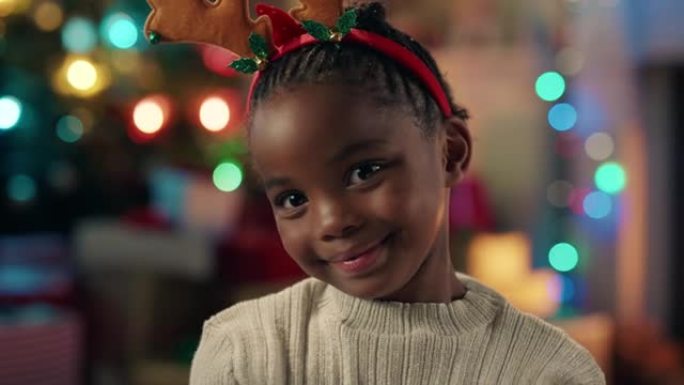 肖像小非洲裔美国女孩庆祝圣诞节穿着有趣的驯鹿鹿角享受节日假期，五颜六色的灯光在家里玩得开心4k镜头