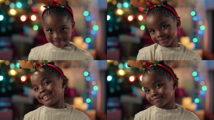 肖像小非洲裔美国女孩庆祝圣诞节穿着有趣的驯鹿鹿角享受节日假期，五颜六色的灯光在家里玩得开心4k镜头