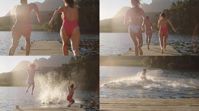 快乐的朋友在日落时从湖边的码头上跳下来，在水中嬉戏，享受自由分享夏季冒险