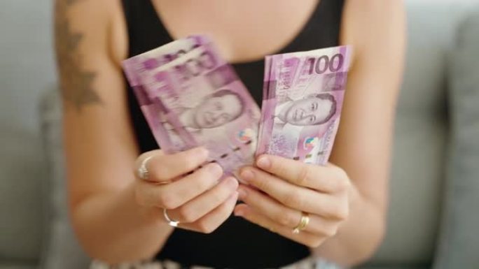 年轻女子在家里数数菲律宾100比索钞票