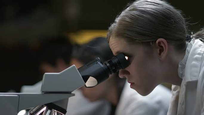 在生物实验室使用显微镜的学生