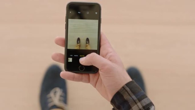 顶视图男子使用智能手机拍摄新鞋的照片在社交媒体上分享摄影享受时尚时尚