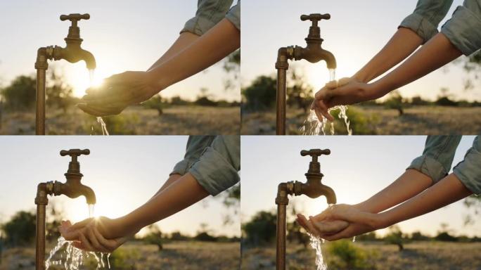 妇女在日出时用淡水在农村农田的水龙头下洗手