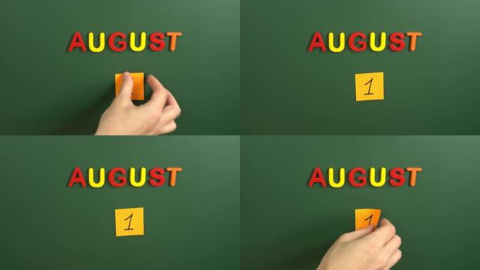 8月1日日历日用手在学校董事会上贴一张贴纸。1 8月日期。8月的第一天。第一个日期号。1天日历。一次