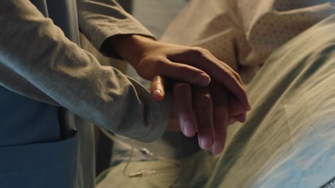 医院护士牵着老妇人的手躺在床上安慰老年患者睡眠康复医疗专业人员在床边给予鼓励医疗保健支持