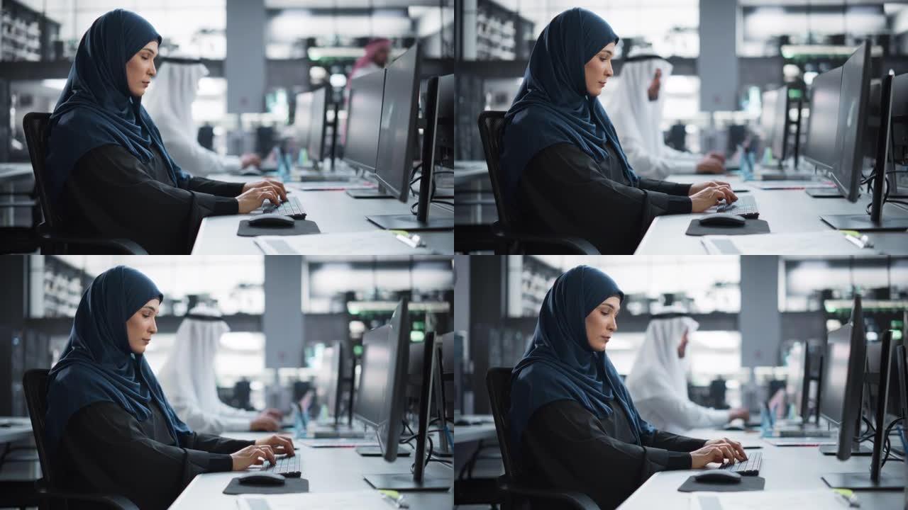 美丽的中东计算机科学家戴着头巾，在技术公司办公室的PC上工作。年轻的穆斯林妇女为一个创新的在线服务项