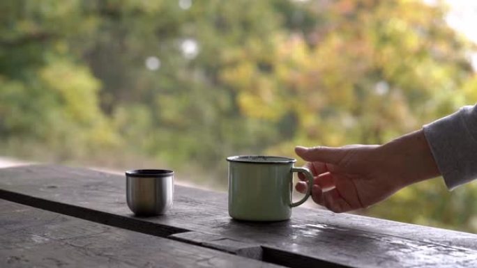 秋天在户外用手拿一个装有热气茶的金属杯