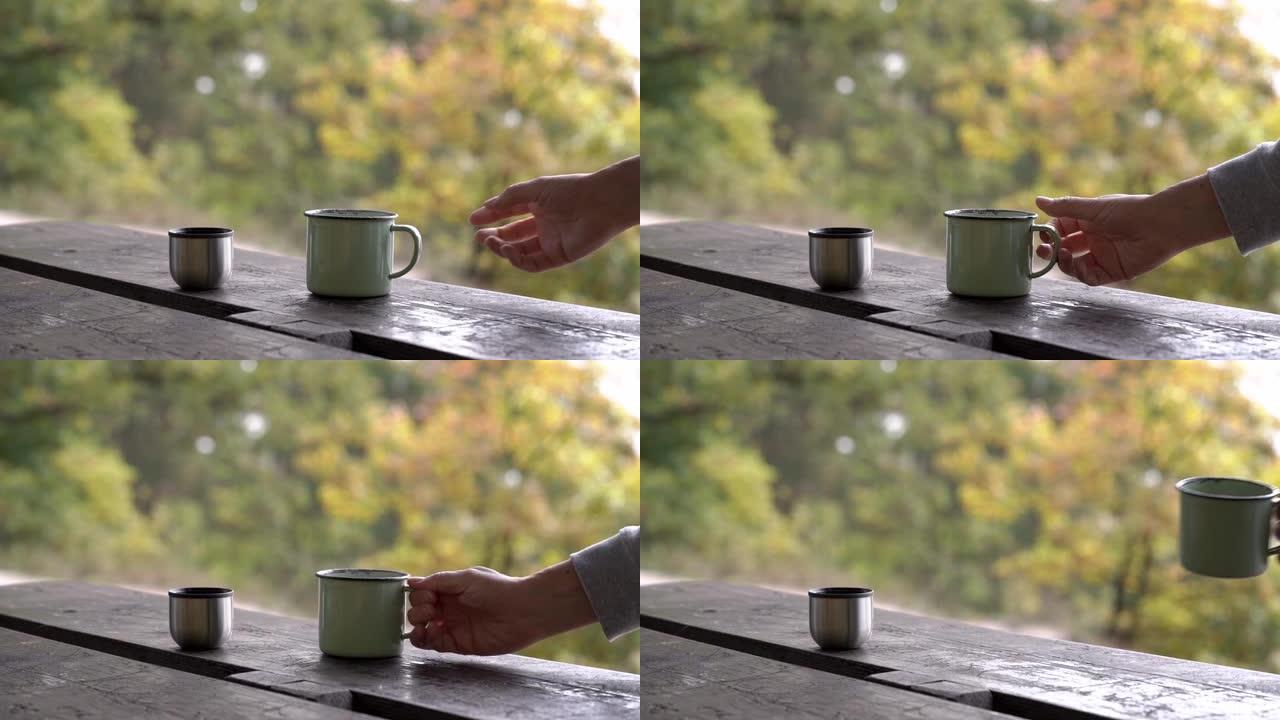 秋天在户外用手拿一个装有热气茶的金属杯