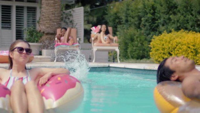 快乐金毛猎犬狗跳进游泳池和朋友一起游泳在充气管上放松享受温暖阳光明媚的4k暑假