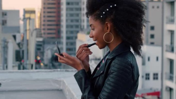 慢镜头，年轻漂亮的非裔美国女性在屋顶上涂口红化妆，准备参加迷人的城市派对，在日落时分穿着时尚的时装