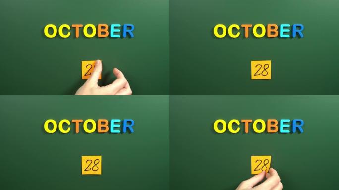 10月28日日历日用手在学校董事会上贴一张贴纸。28 10月日期。10月第二十八天。第28个日期号。