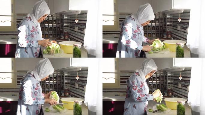 中年穆斯林妇女在厨房煮花椰菜，食品上戴着头巾。在家中的伊斯兰女性。家庭主妇日常家庭生活常规。