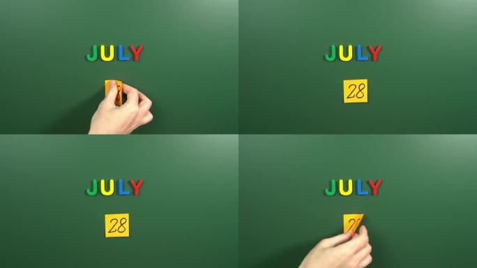 7月28日日历日用手在学校董事会上贴一张贴纸。28 7月日期。7月第二十八天。第28个日期号。28天