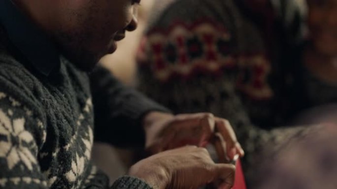 年轻的非洲裔美国男子打开圣诞礼物打开包装礼物享受新袜子与家人和朋友在家庆祝节日4k
