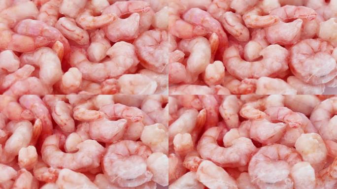 粉红色新鲜冷冻虾，带冰圈旋转。未煮熟的海鲜特写背景。冷冻对虾、美味佳肴、海鲜