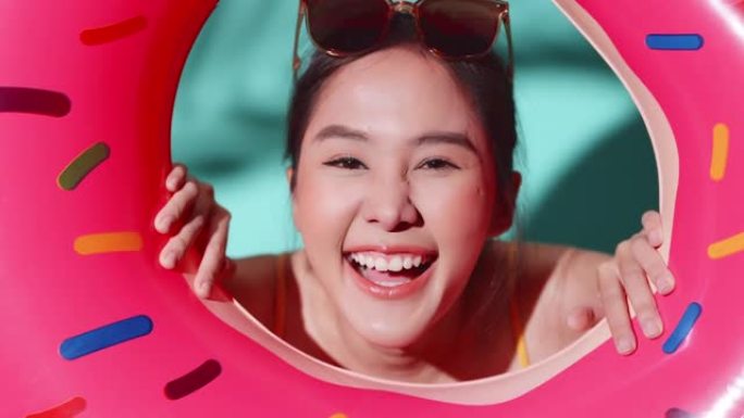 你好夏天问候年轻的亚洲女性泳装俏皮快乐有趣玩脸表情手势握着甜甜圈形状充气，女人准备在夏天玩得开心放松