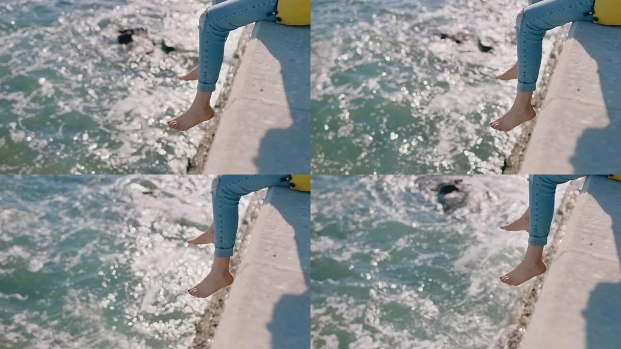 女人腿悬在水面上赤脚女孩享受暑假坐在海边码头看海浪自由概念