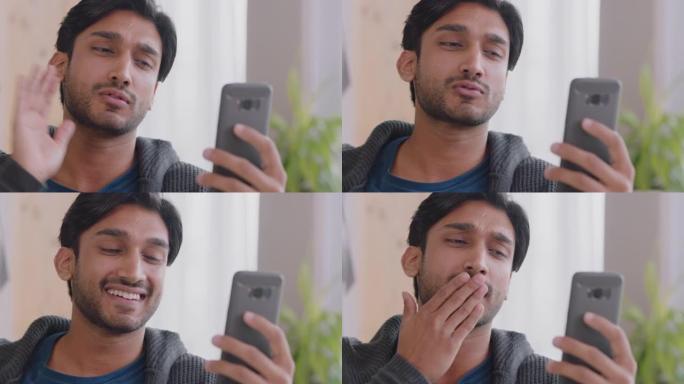 快乐的印度男子使用智能手机进行视频聊天，挥舞着婴儿吹吻，享受在家中的手机聊天