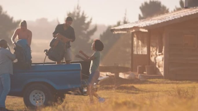 一群朋友在日落时分到乡村小屋的公路旅行中从卡车上卸下背包-慢动作拍摄