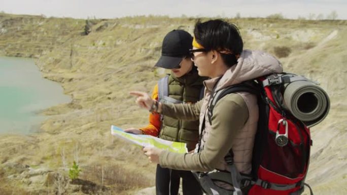 两名亚洲女性游客白天在岩石湖海岸学习地图