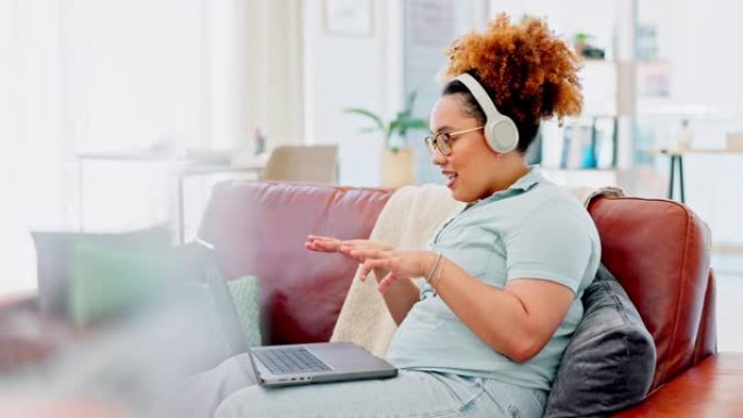 笔记本电脑，wave和黑人妇女在家里的沙发上戴着耳机进行视频通话，以进行在线会议。自由职业者，远程工