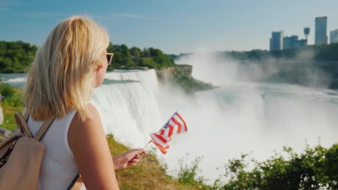 一名手持美国国旗的女子在欣赏尼亚加拉大瀑布，这是美国最著名的景点之一