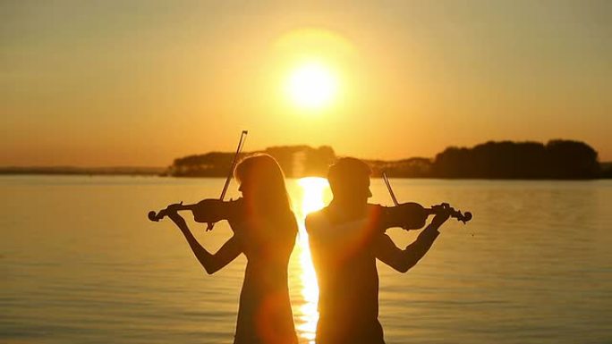 男人和女人在日落时拉小提琴
