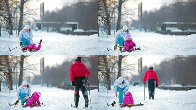 摔倒孩子并帮助母亲滑雪